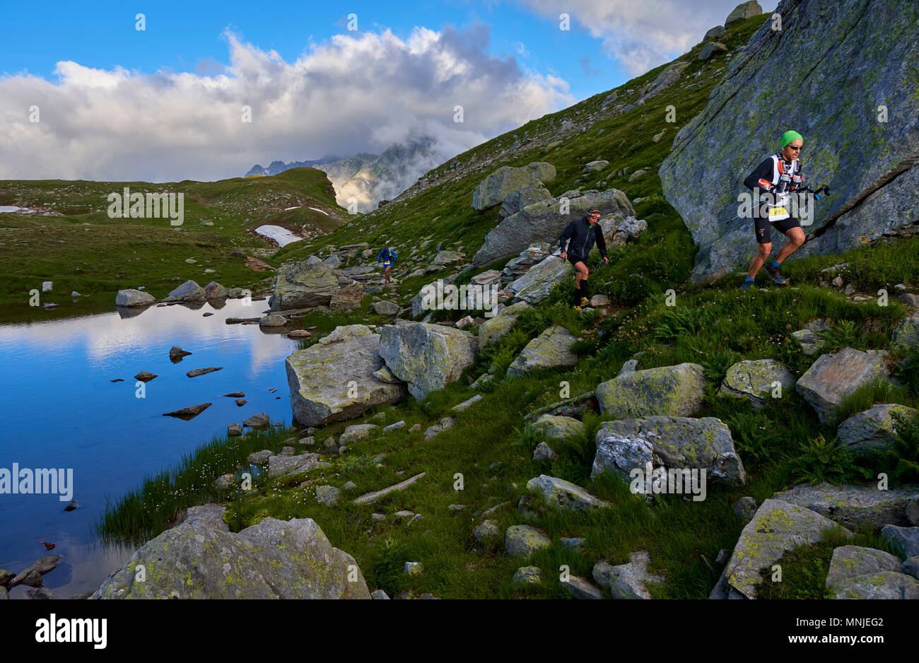 Le persone che eseguono in un paesaggio collinare con massi durante le ore diurne, Alpe Devero, Verbania, Italia Foto Stock