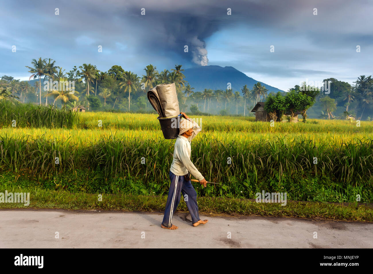 Uomo che cammina su una strada e vulcano Agung in background.Bali.Indonesia Foto Stock