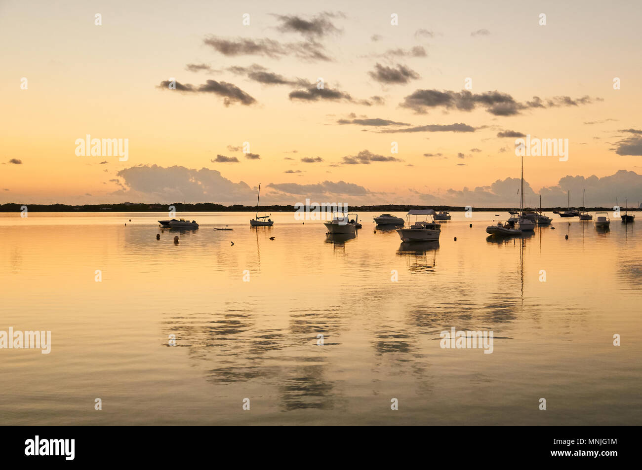 Ancorate le barche a vela e le nuvole la riflessione al tramonto a Estany des Peix marine lagoon a La Savina (Formentera, isole Baleari, Spagna) Foto Stock