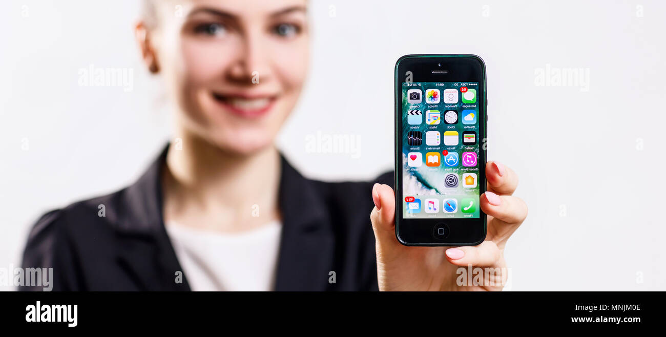 Giovane donna trattiene il nero per Apple iPhone 5 display in mano. Foto Stock