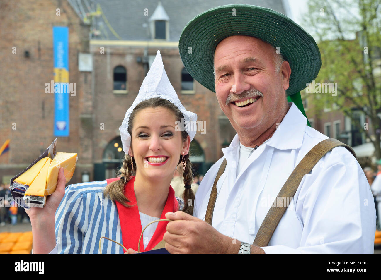 Coppia attraente la vendita di formaggi per la folla onlooking presso il mercato del formaggio di Alkmaar, Olanda, Netherlads Foto Stock