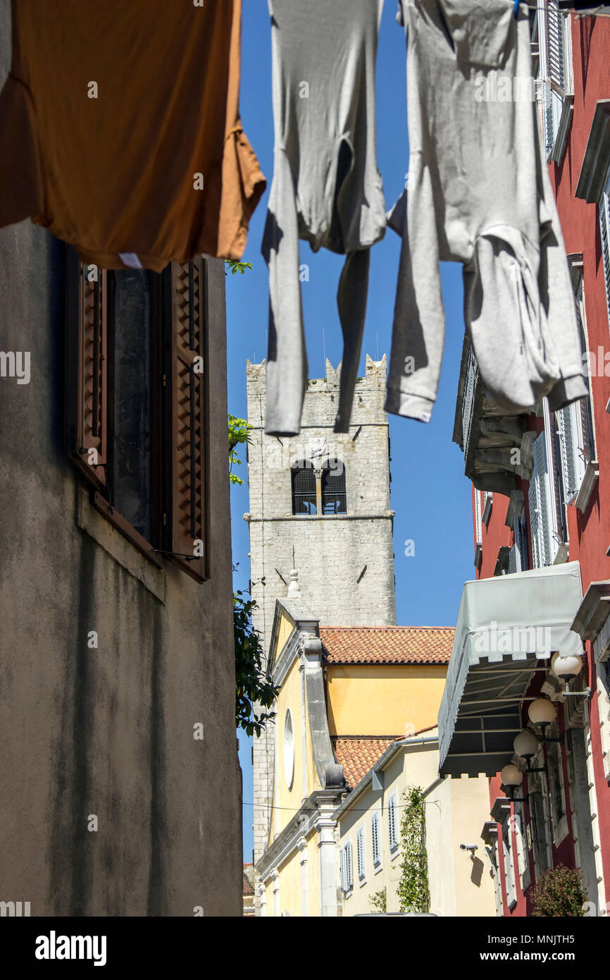 Istria centrale, Croazia - torre campanaria vista da una tipica strada stretta con stendibiancheria su linee di lavaggio nell'antica città di Motovun Foto Stock