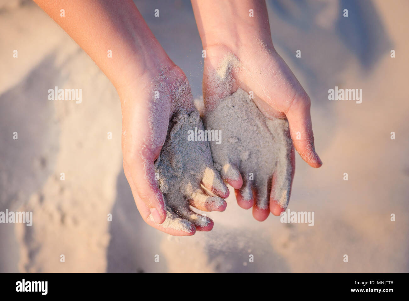 Mani femminili pour la sabbia sul terreno. Foto Stock