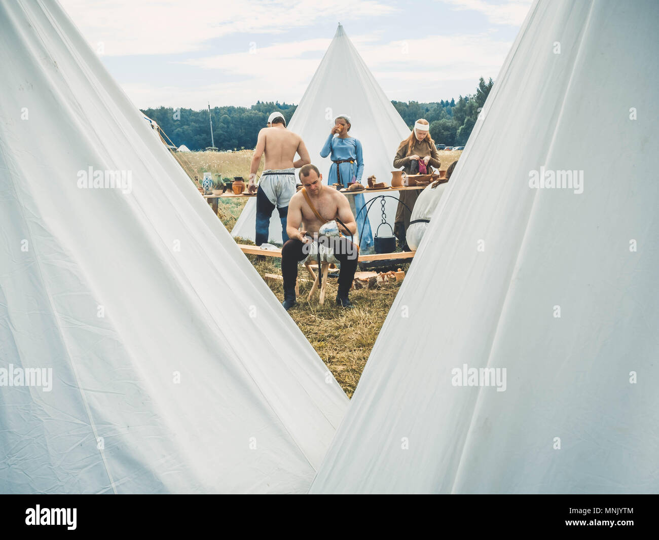 RITTER WEG, MOROZOVO, Aprile 2017: Outdoor scena medievale di modo di vita. Il ragazzo pulisce il casco dopo una improvvisata battaglia di cavalieri. Sullo sfondo, un campo di cucina e un accampamento medievale. Foto Stock