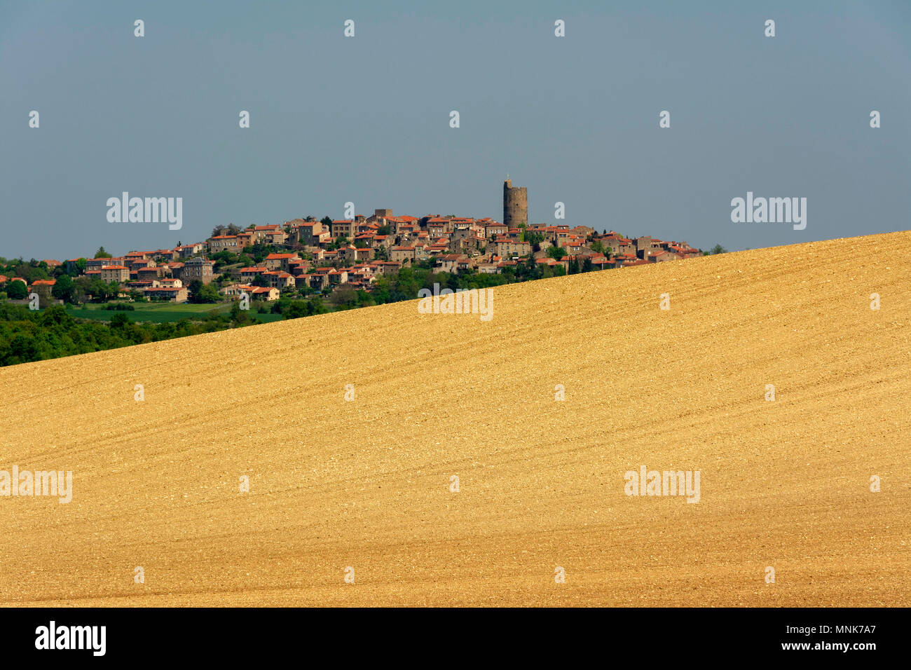 Villaggio di Montpeyroux e campo arato con l'orizzonte. Limonese. Puy de Dome. Auvergne. Francia Foto Stock