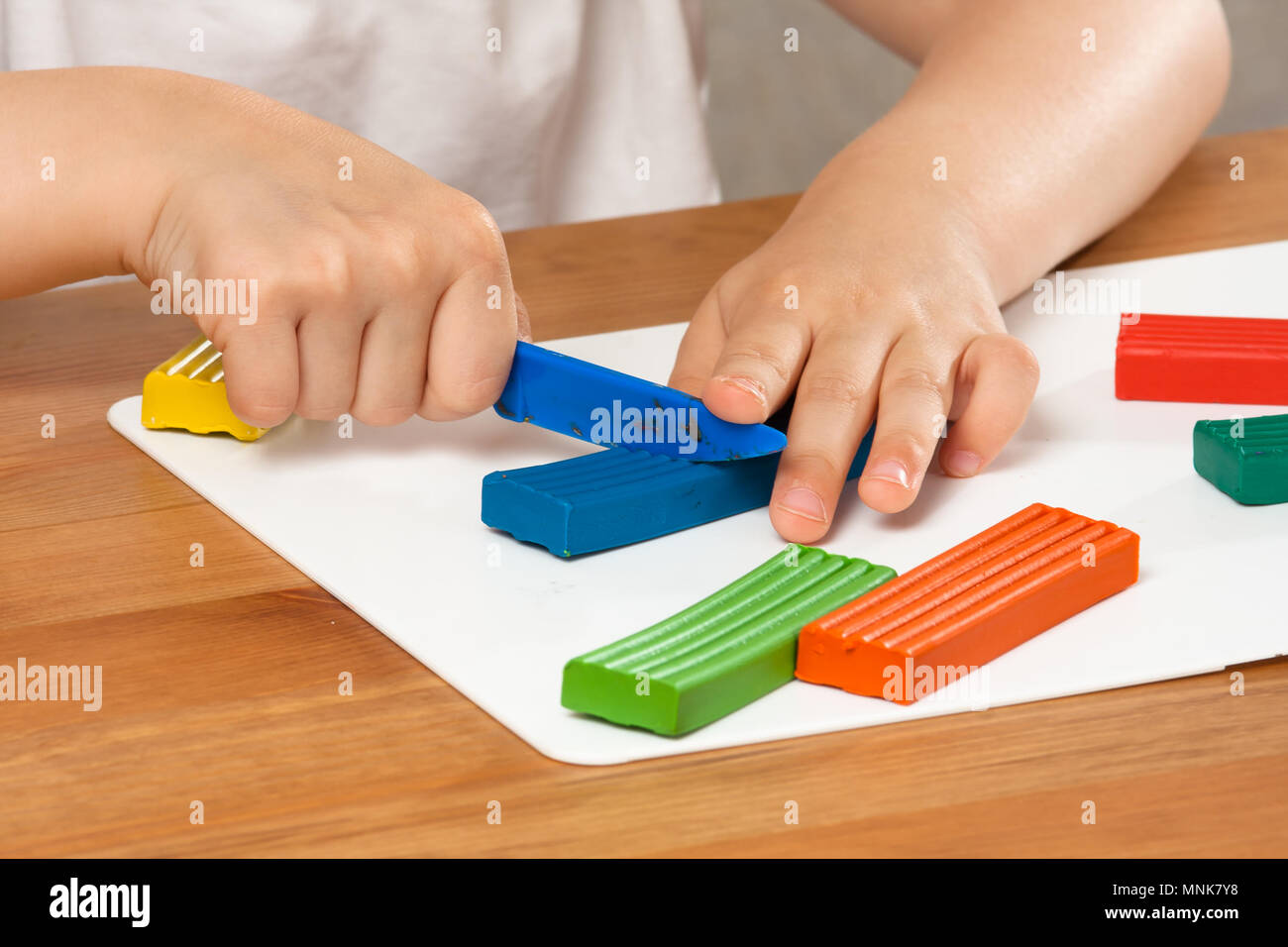 Le mani del bambino di plastilina di taglio con un coltello in plastica Foto Stock