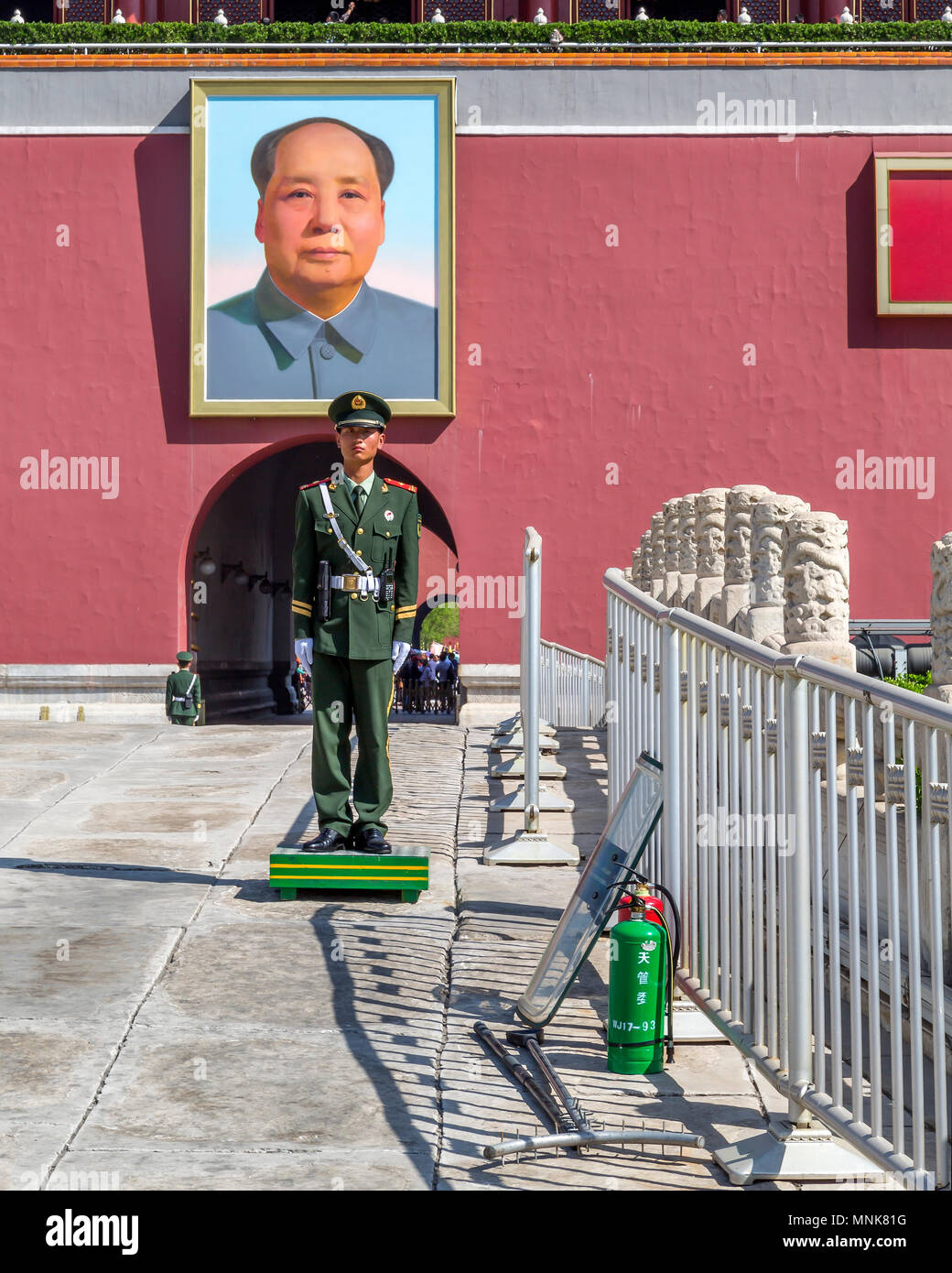 Un soldato cinese sta di guardia sotto il ritratto di Mao Zedong in piazza Tiananmen Gate, Pechino, Cina. Il suo scudo antisommossa si appoggia contro la ringhiera. Foto Stock