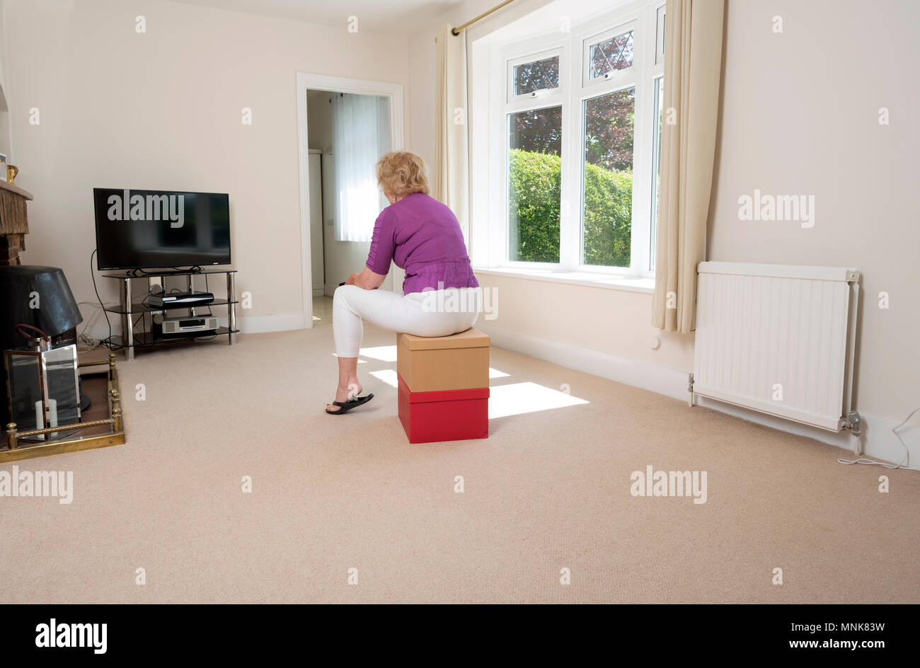 Casa in movimento. La donna in un vicino di camera vuota con controller tv Foto Stock