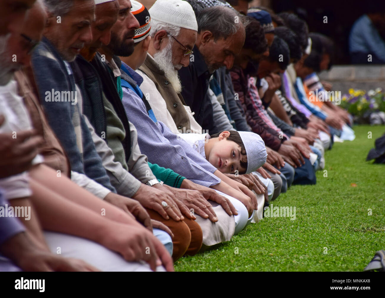 Mentre altri sono in preghiera un musulmano del Kashmir boy guarda il primo venerdì del santo mese di digiuno del Ramadan nel giardino della Jamia Masjid o Grande Moschea, a Srinagar, Kashmir indiano. L Islam è più sacro mese del Ramadan è un periodo di intensa preghiera, alba a digiuno al tramonto e feste serali. Foto Stock