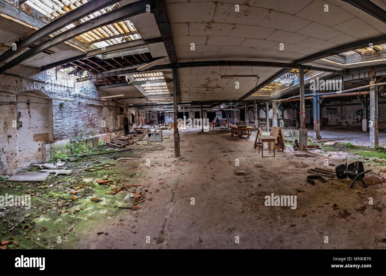 Sala desolato di una fabbrica di rovina. I raggi di luce sono brilla attraverso le finestre rotte Foto Stock