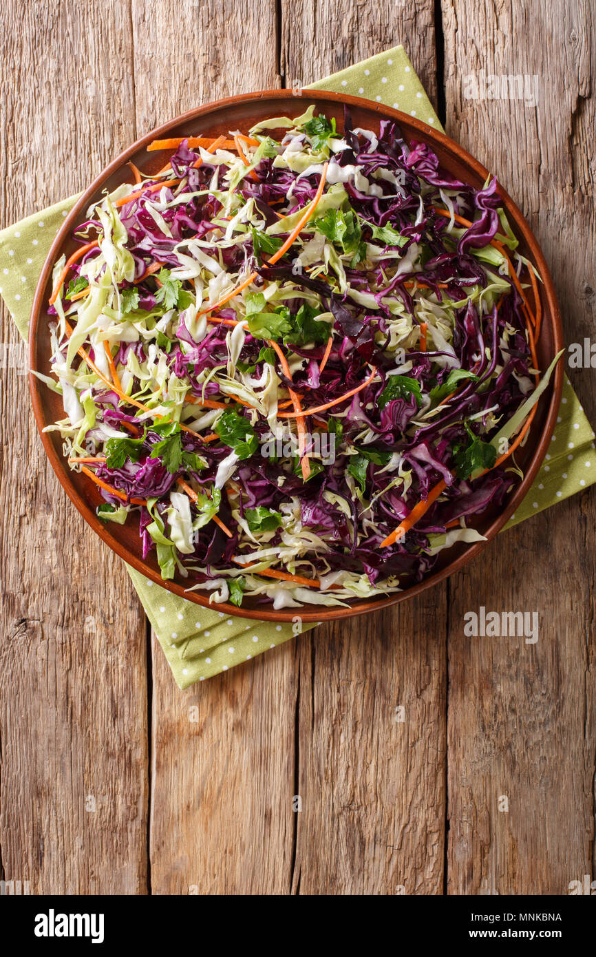 Vegetariano insalata di cavoli bianchi e cavoli rossi con carote conditi con olio di oliva close-up su una piastra. Verticale in alto vista da sopra Foto Stock