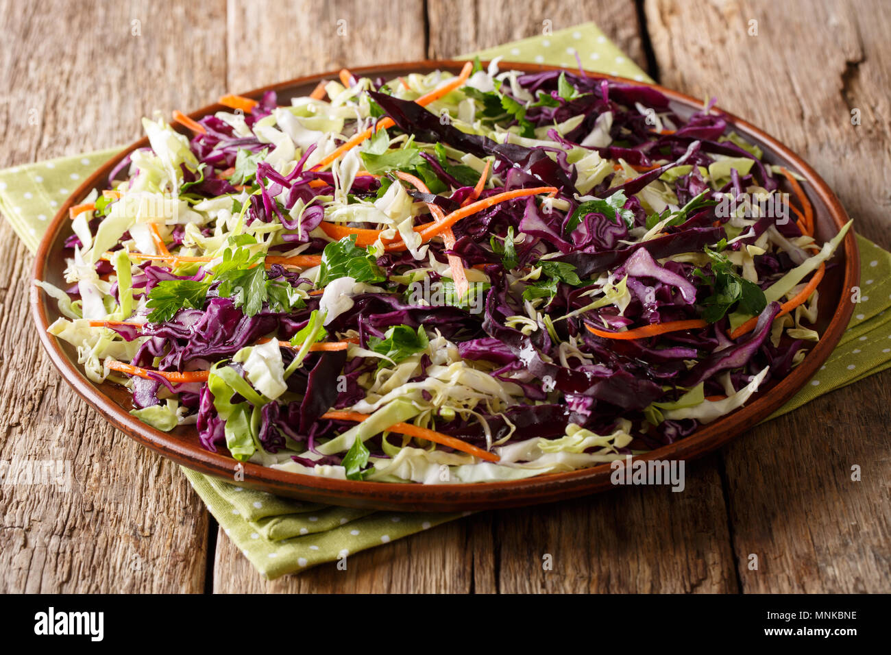 Mix insalata di cavoli bianchi e cavoli rossi con carote, cipolle, erbe con olio di oliva close-up su una piastra su un piano orizzontale. Foto Stock