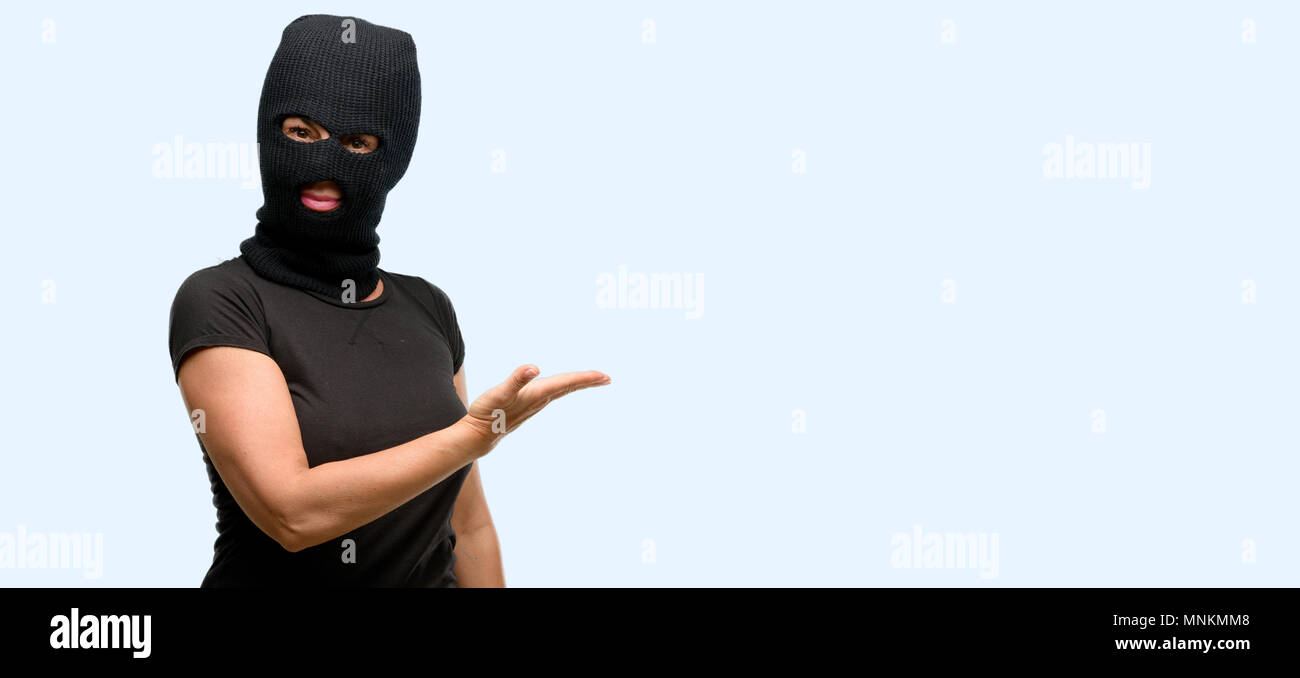 Ladro terrorista donna che indossa passamontagna maschera da sci tenendo  qualcosa in mano vuoto isolato sfondo blu Foto stock - Alamy