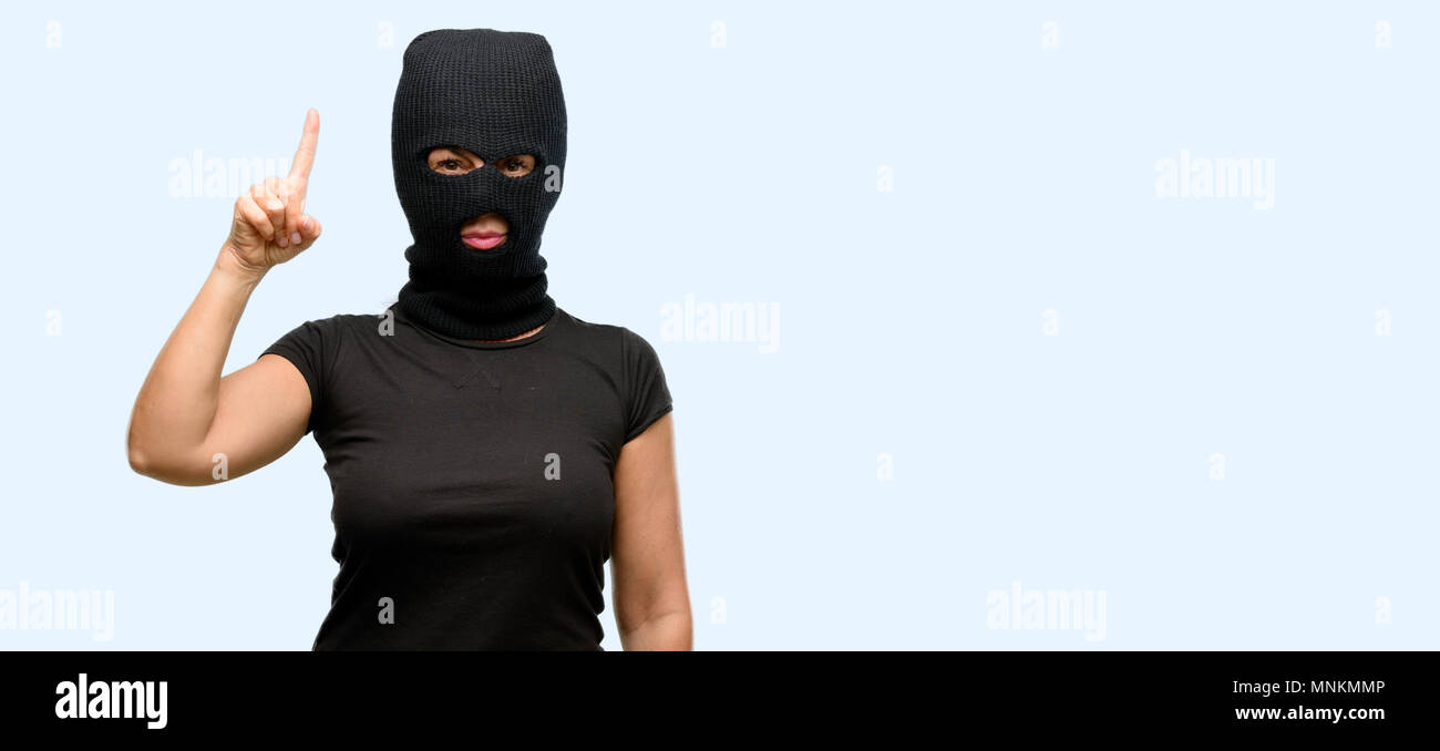 Ladro terrorista donna che indossa passamontagna maschera da sci sollevando  il dito, il numero uno isolato sfondo blu Foto stock - Alamy