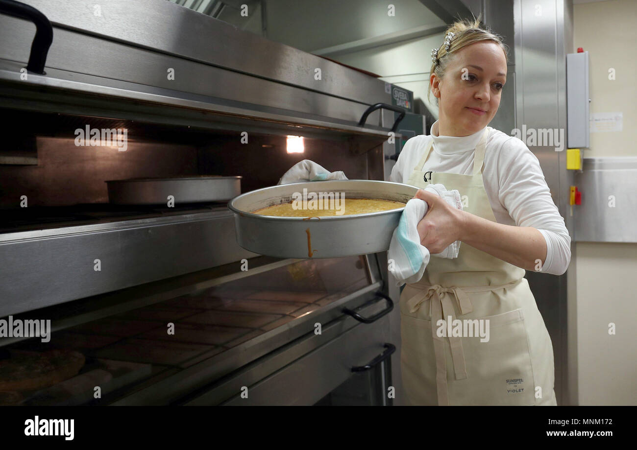 Claire Ptak, proprietario di violetta panificio a Hackney, a est di Londra, porta la parte della torta per le nozze del principe Harry e Meghan Markle fuori del forno nelle cucine a Buckingham Palace a Londra. Foto Stock