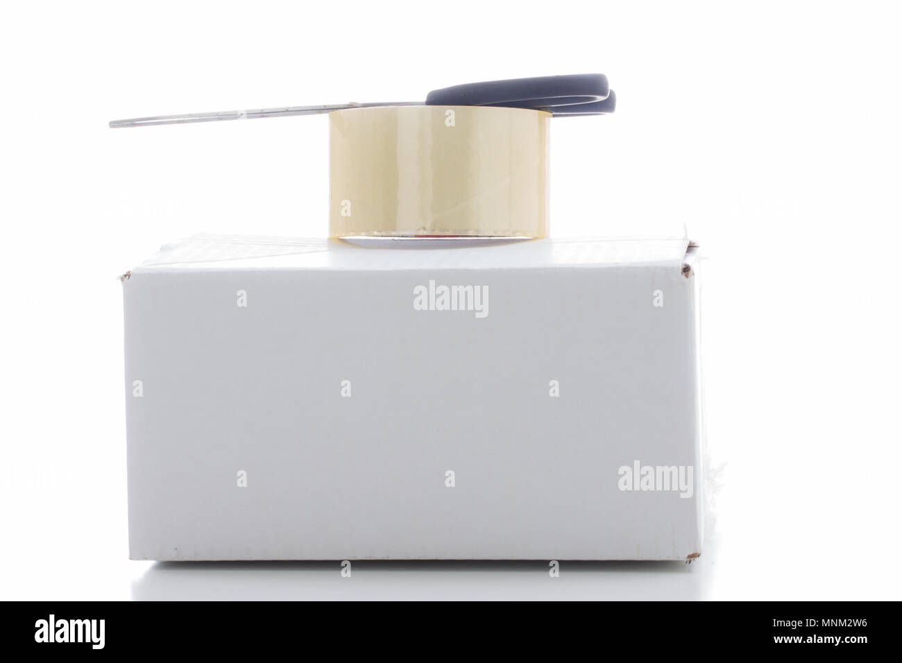 White cartone di spedizione, nastro adesivo trasparente e nero forbici sono impilati uno sull'altro Foto Stock