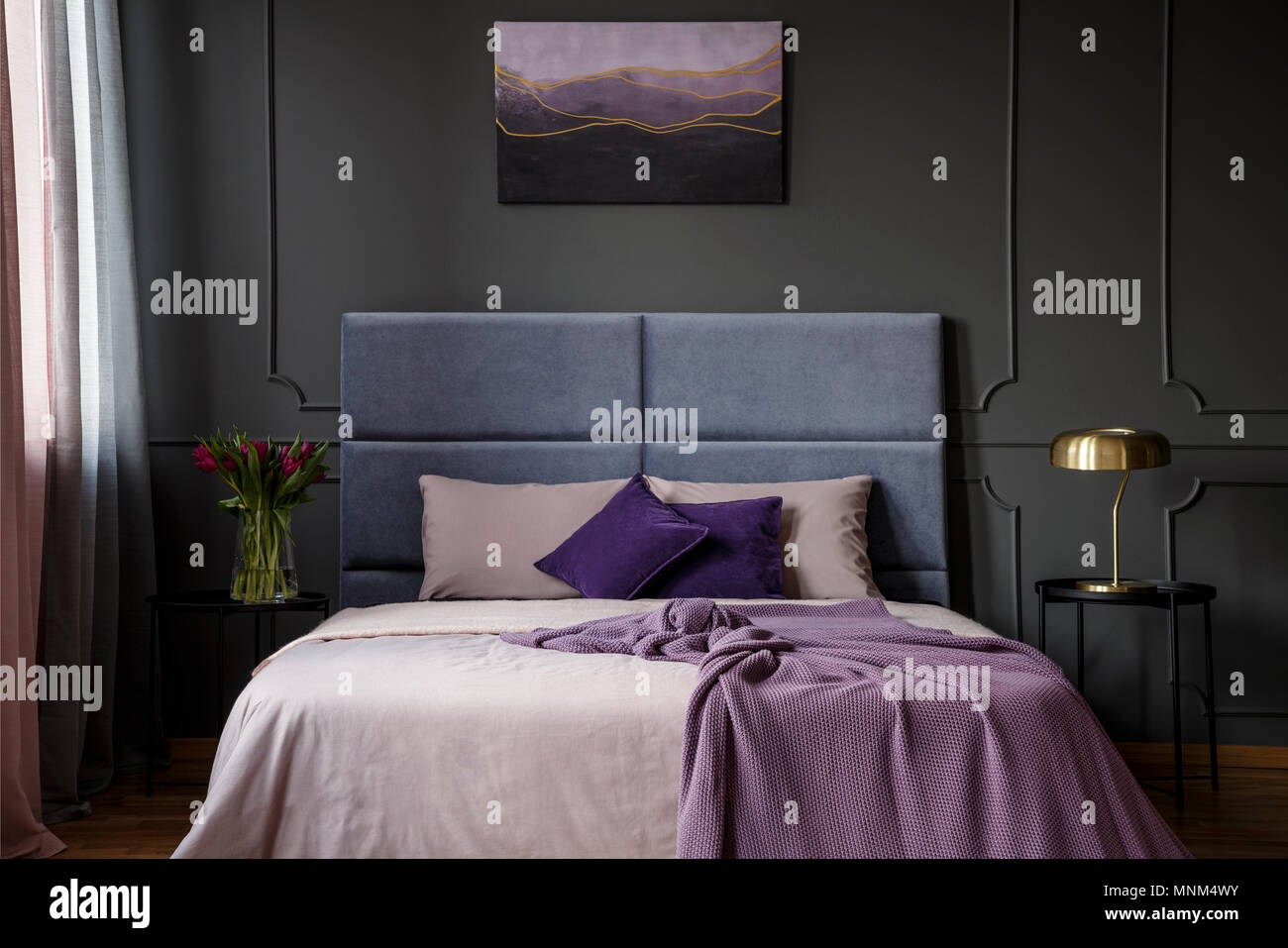 Oro lampada sul tavolo accanto al letto di Violetta hotel bedroom interno con fiori e pittura su parete con lo stampaggio Foto Stock