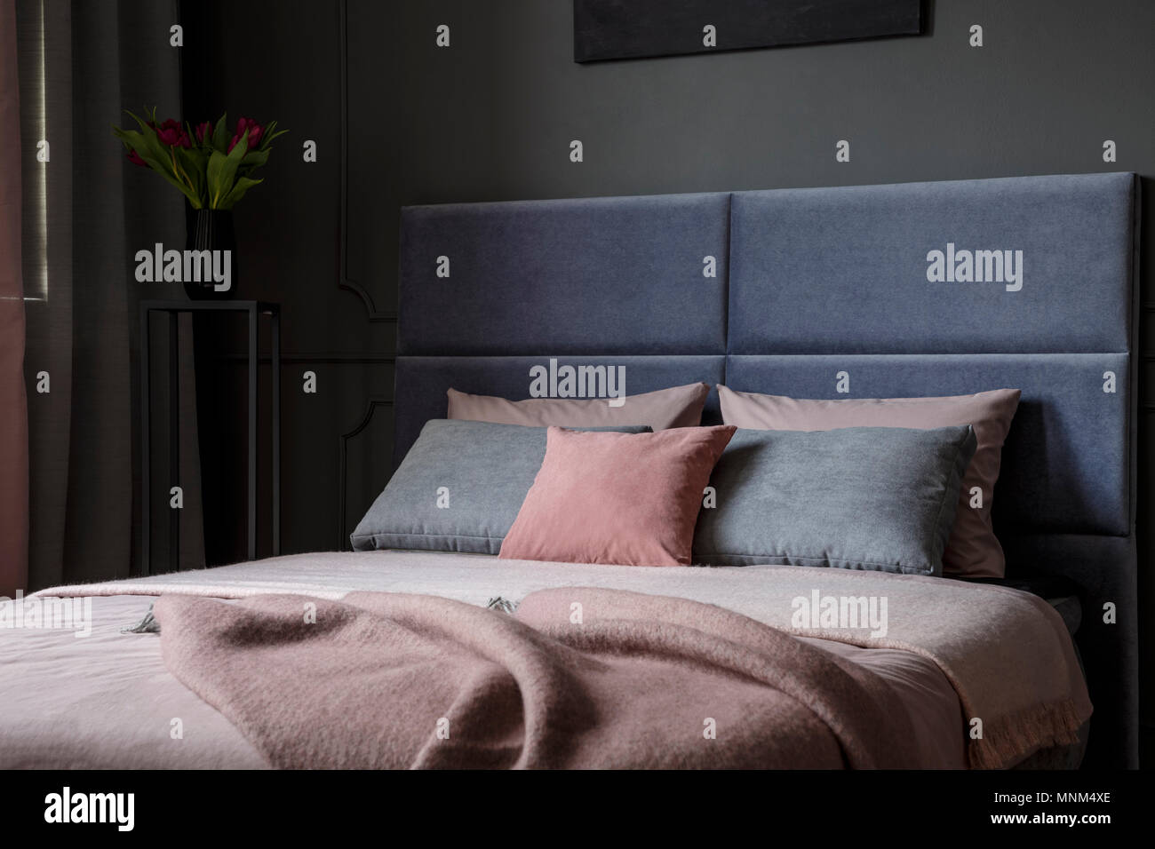 Close-up di rosa e grigio cuscino sul letto con coperte e testiera in interiore camera da letto Foto Stock