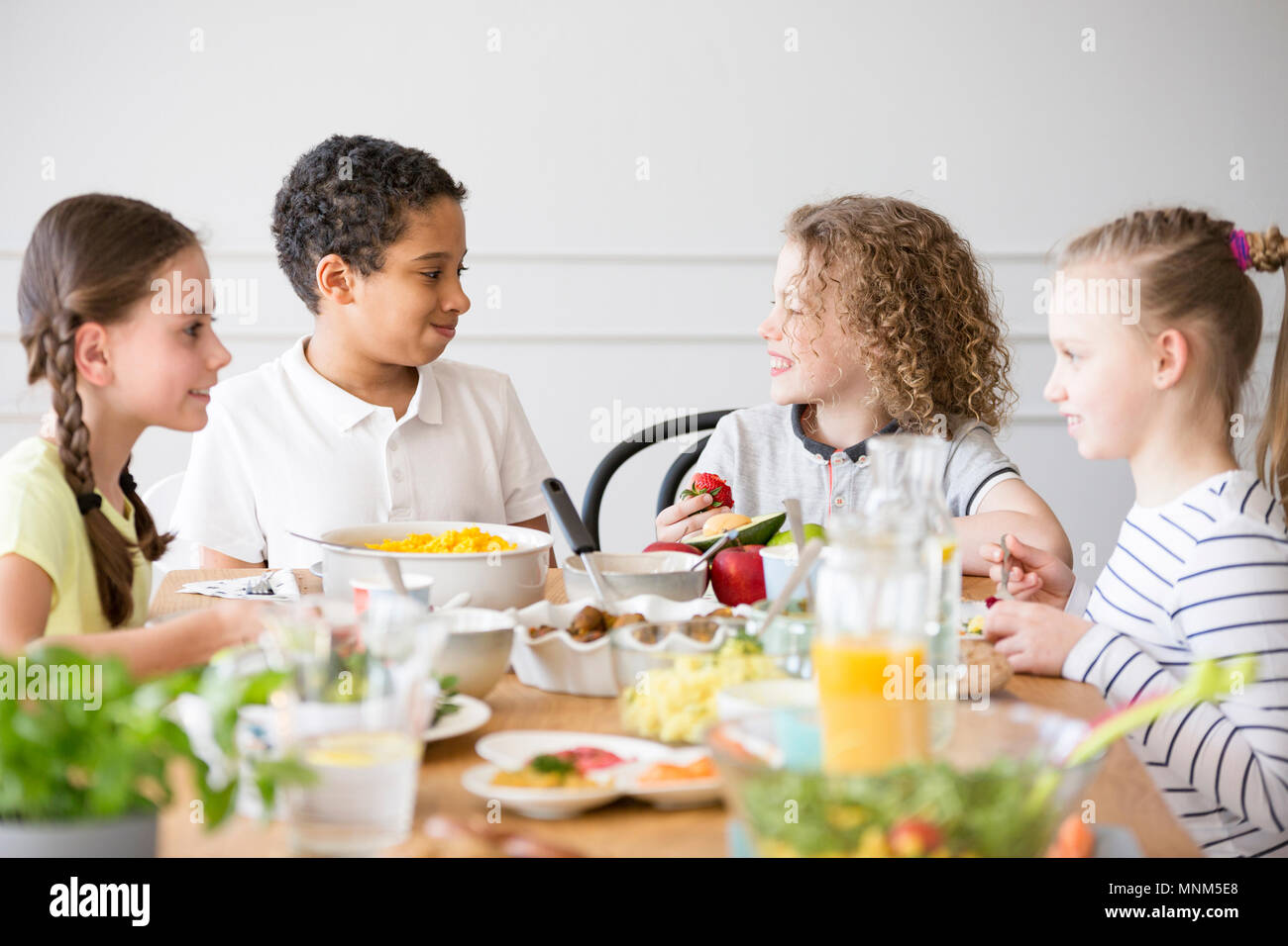 Sorridente gruppo multiculturale dei bambini a mangiare cibo durante la festa di compleanno Foto Stock