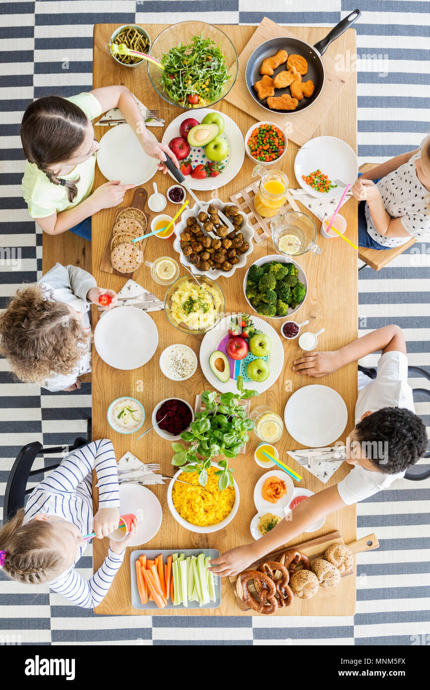 Vista dall'alto sui bambini mangiare sano la cena al tavolo durante la festa di compleanno Foto Stock