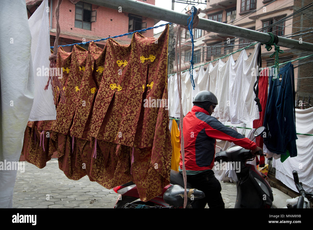 Il Nepal, Kathmandu. Un uomo parcheggia la sua scooter tra servizio lavanderia Foto Stock