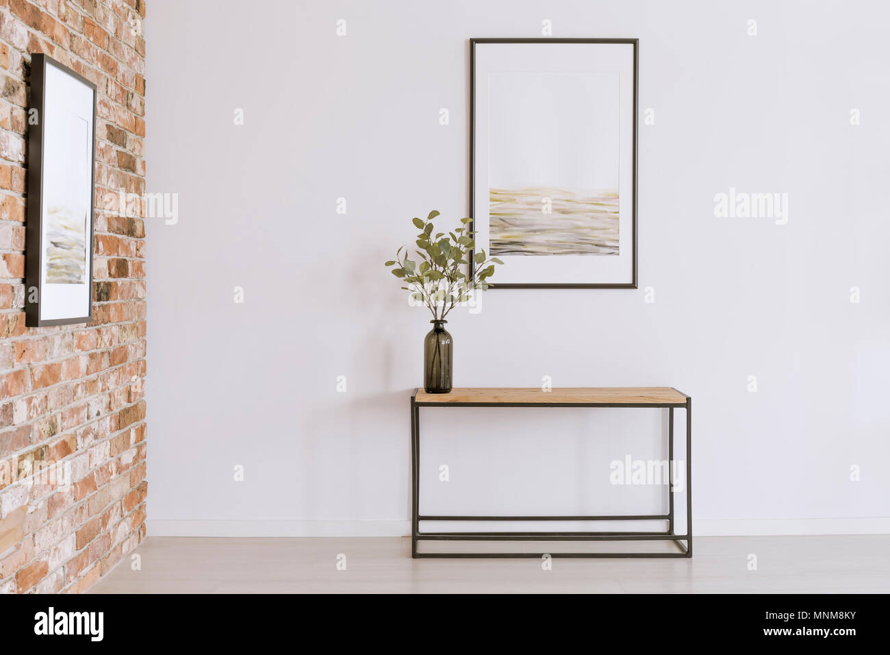 Semplice poster sul muro bianco sopra la tabella con piante in vaso nero in galleria d'arte Foto Stock