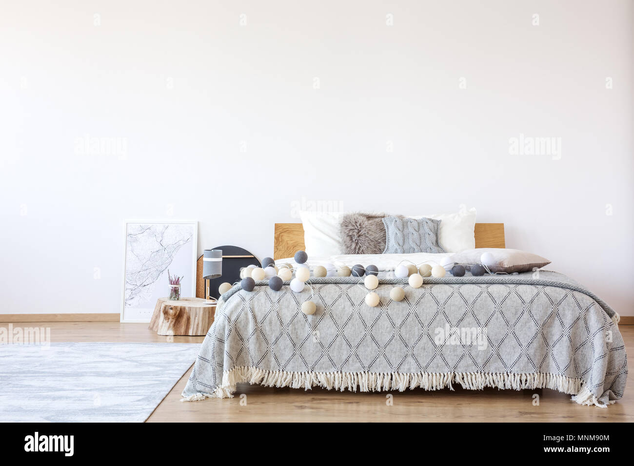 Poster che giace accanto a un letto doppio con bianco, beige e grigio palline di cotone su di esso Foto Stock