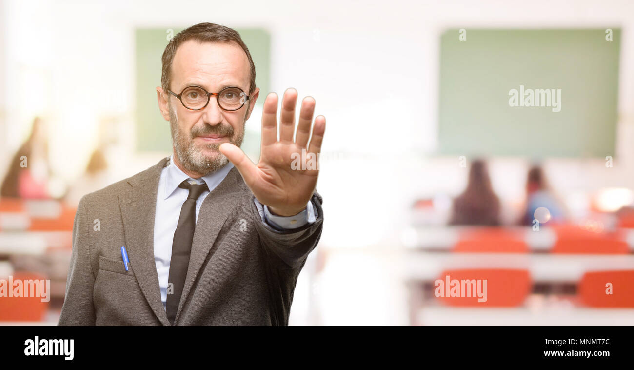 Insegnante uomo utilizzando bicchieri infastiditi con cattivo atteggiamento facendo segno di stop con mano, dicendo no, esprimendo la sicurezza, difesa o di restrizione, forse spingendo Foto Stock