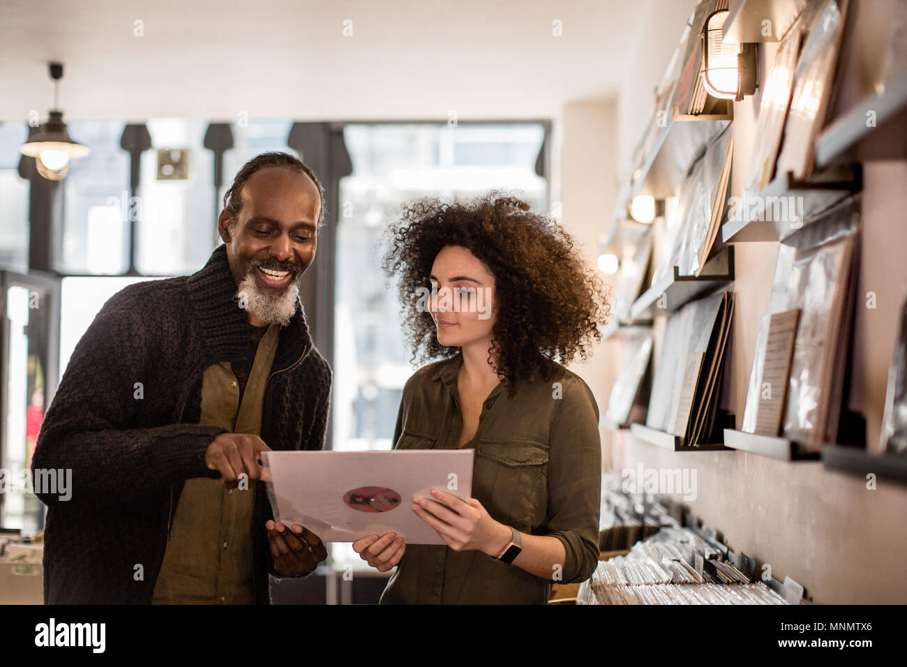 Il proprietario del negozio aiutando il cliente in un archivio di record Foto Stock