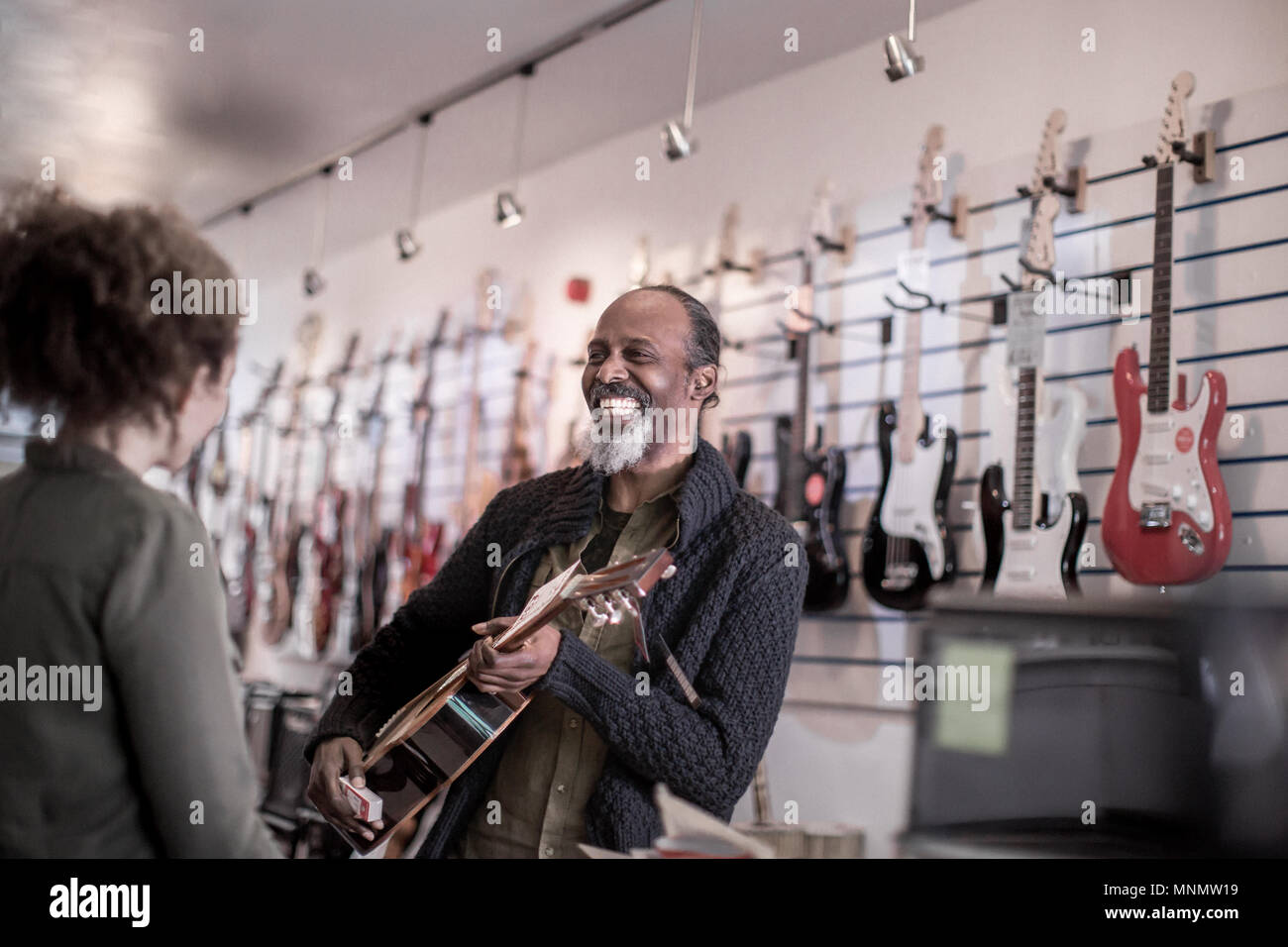 Maschio senior a suonare la chitarra in negozio Foto Stock