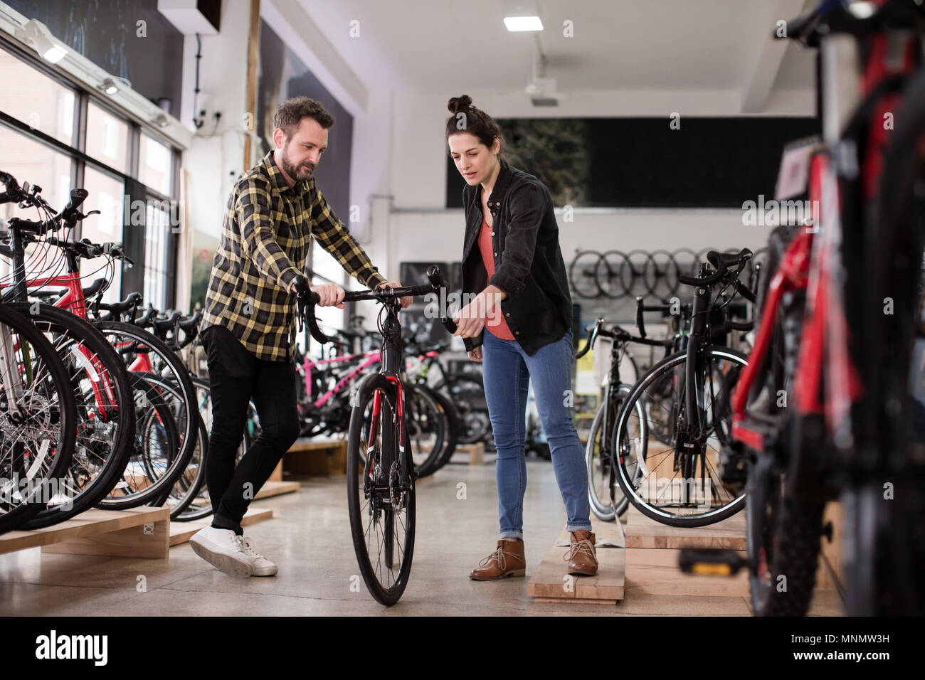 Titolare di una piccola azienda che serve il cliente in un negozio bike Foto Stock
