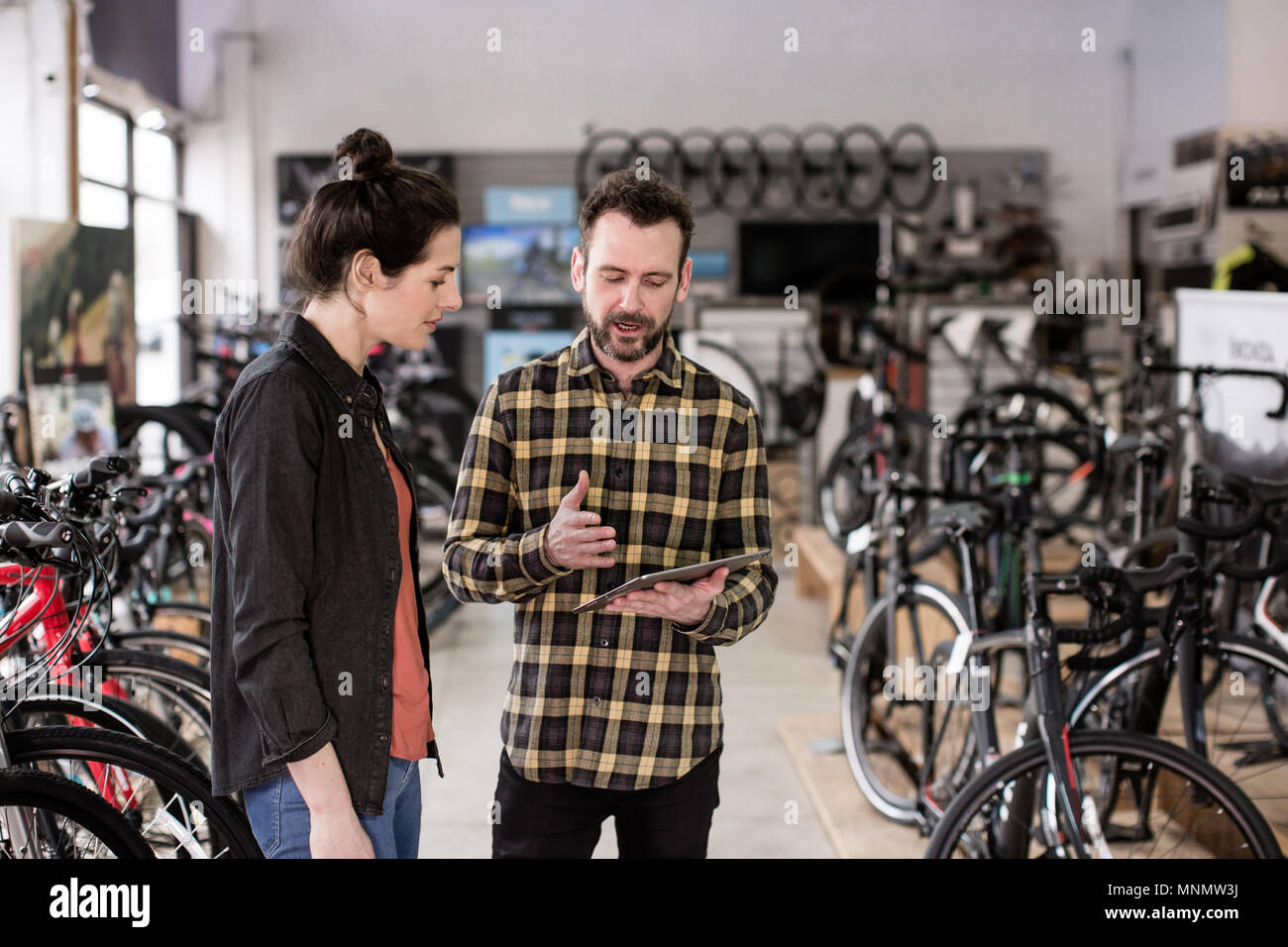 Titolare di una piccola azienda che serve il cliente in un negozio bike Foto Stock