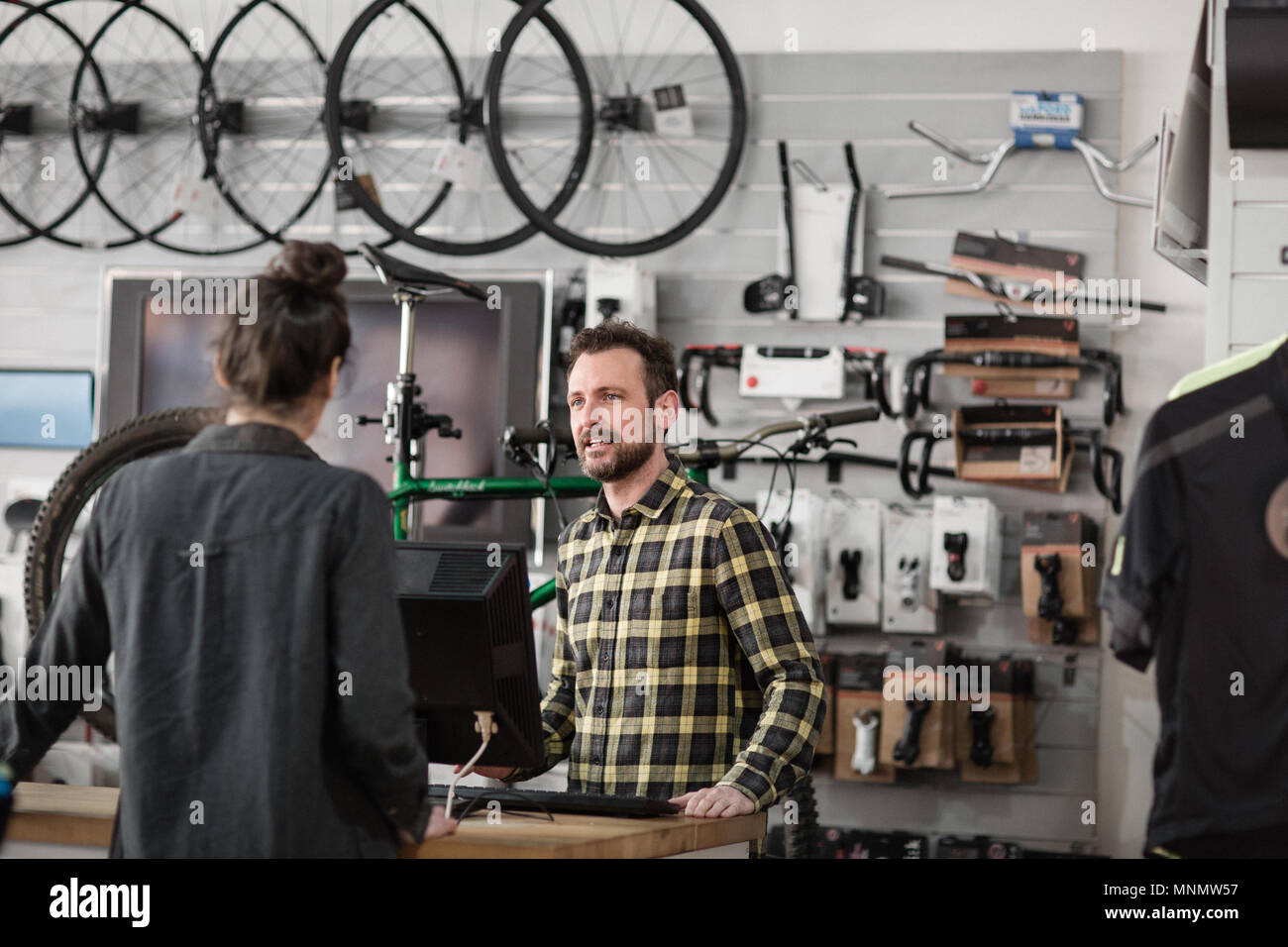 Titolare di una piccola azienda che serve il cliente in un negozio di biciclette Foto Stock