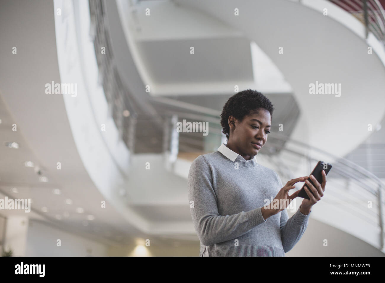 African American utilizza lo smartphone in un ufficio moderno Foto Stock