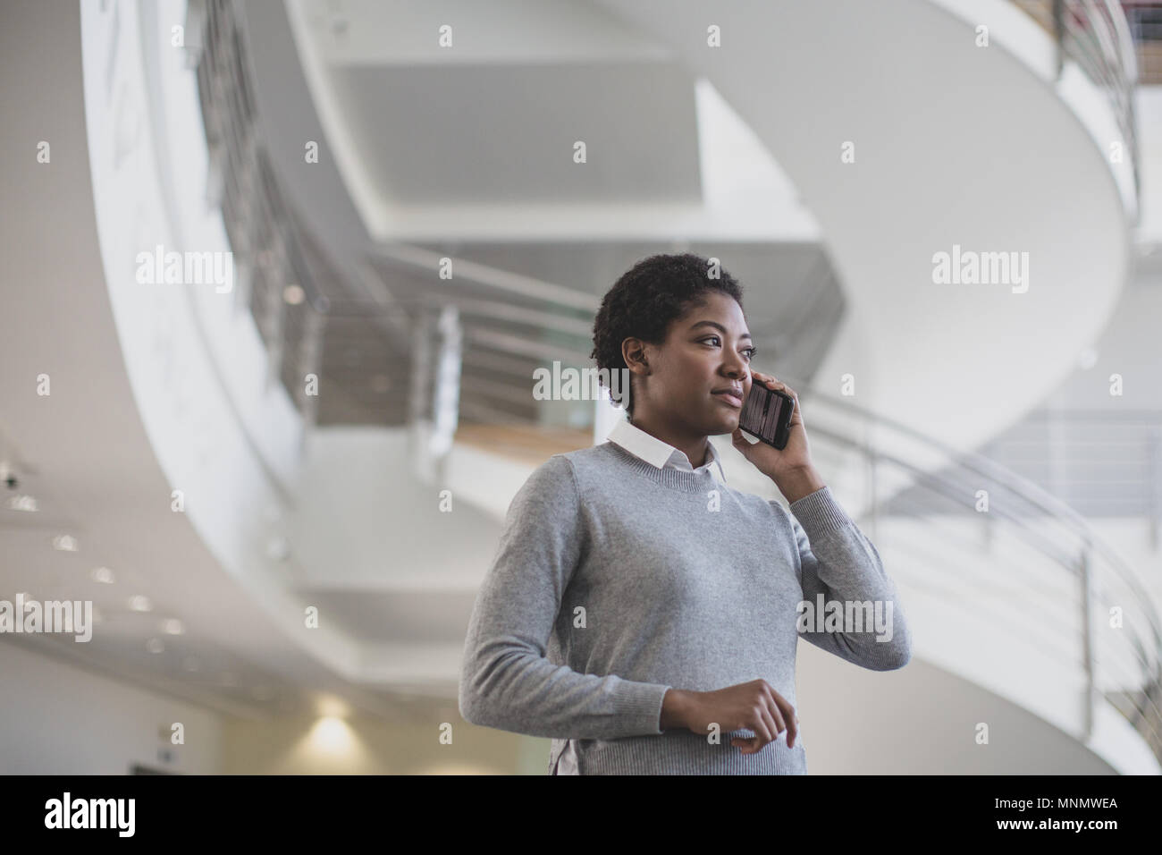 African American utilizza lo smartphone in un ufficio moderno Foto Stock