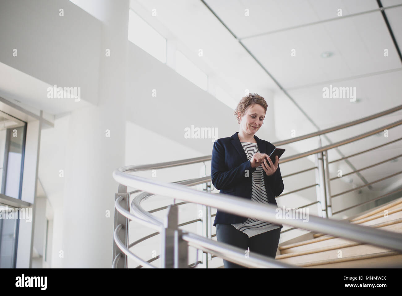 Imprenditrice utilizza lo smartphone in un ufficio moderno Foto Stock