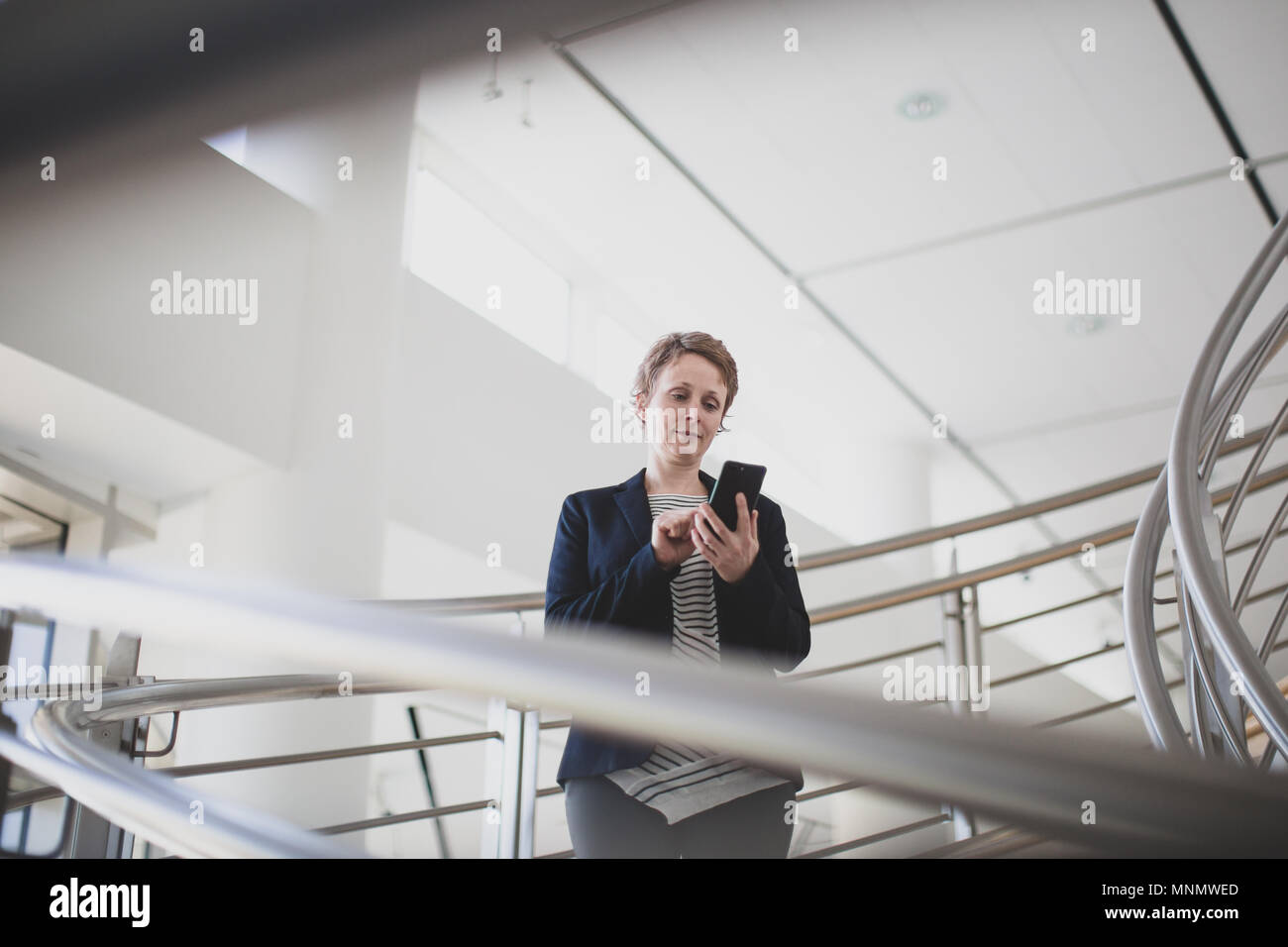 Imprenditrice utilizza lo smartphone in un ufficio moderno Foto Stock