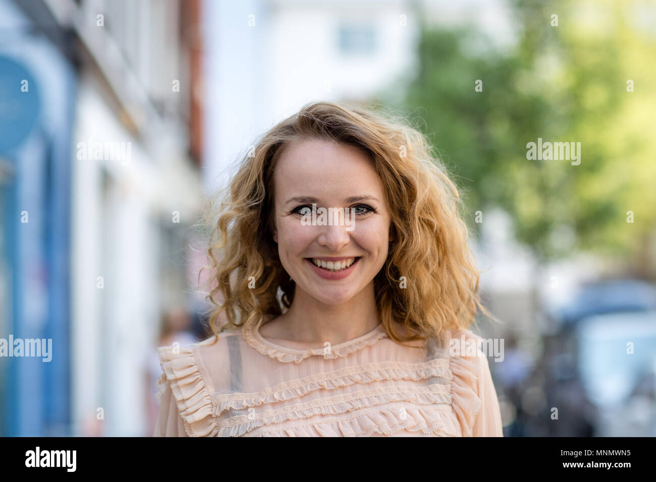 Femmina adulta sorridente alla fotocamera all'aperto in città Foto Stock