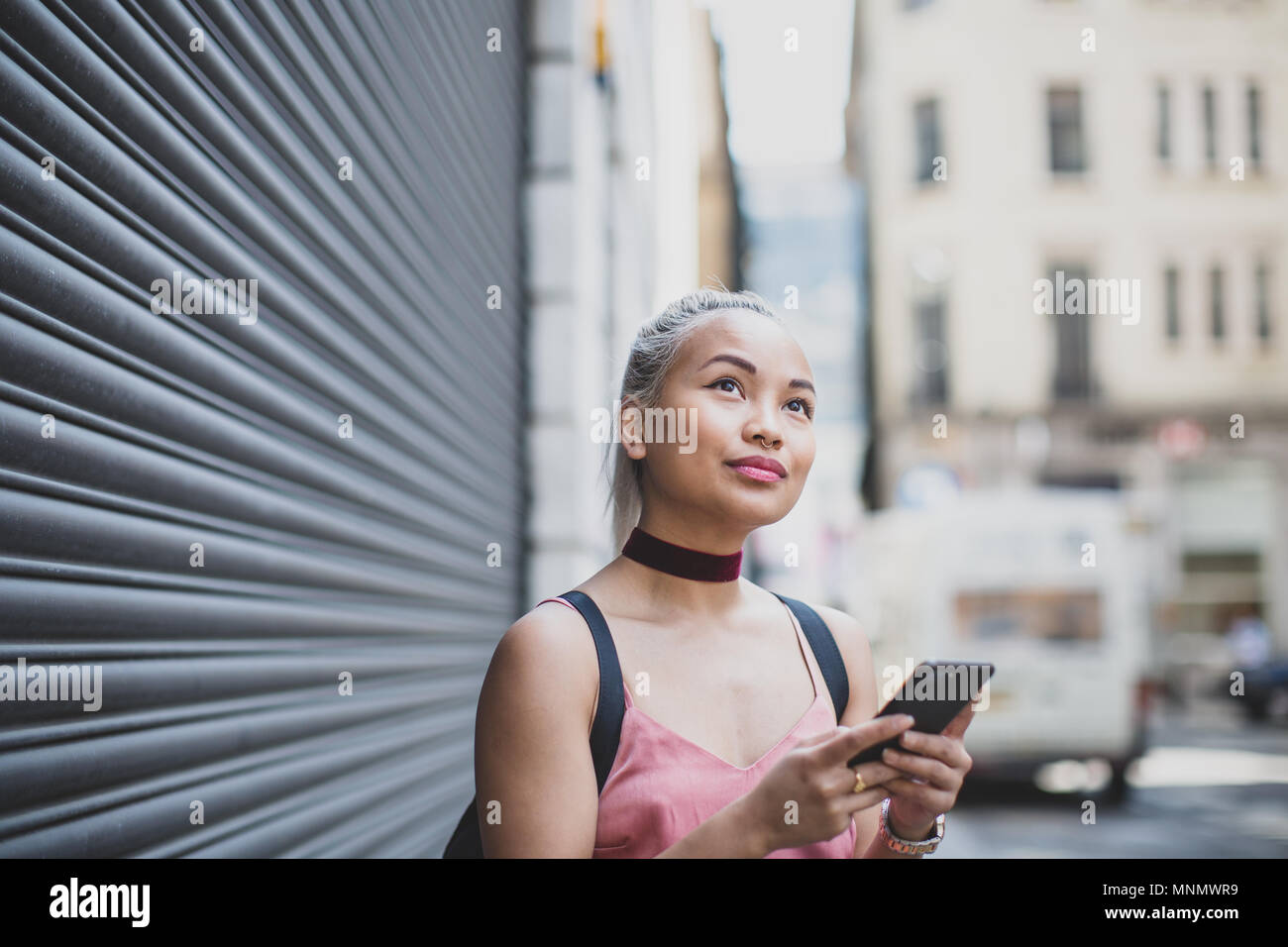 Giovane femmina adulta utilizza lo smartphone su strada Foto Stock