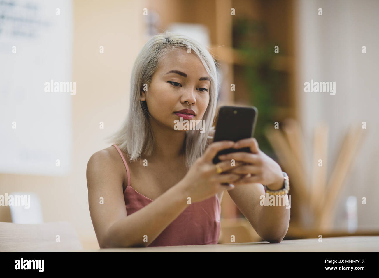 Giovane femmina adulta utilizzando lo smartphone nel college Foto Stock