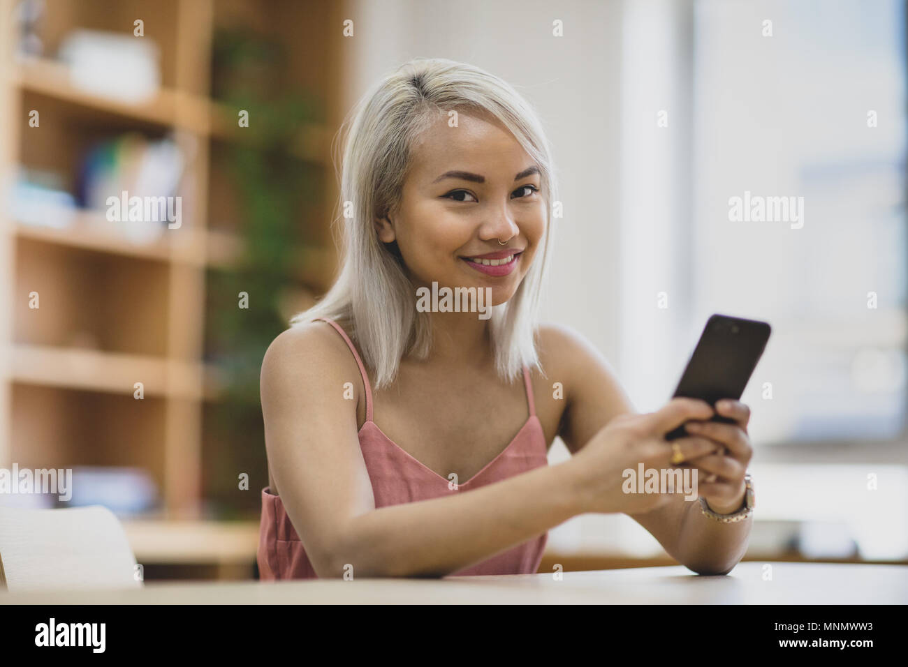 Giovane femmina adulta utilizzando lo smartphone nel college Foto Stock