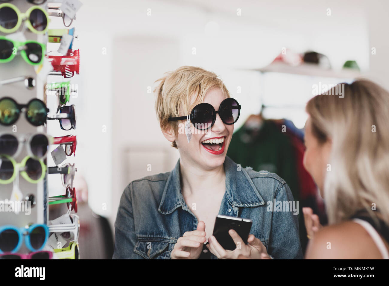 Millennial cercando su occhiali da sole in un negozio vintage Foto Stock
