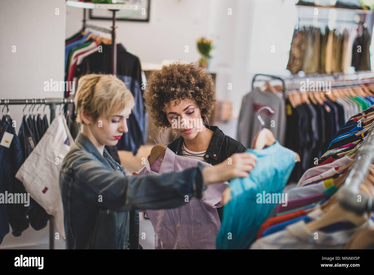 Femmina millenario amici shopping in un vintage negozio di abbigliamento Foto Stock