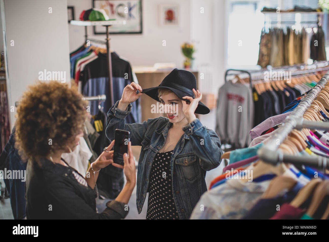 La millenaria cercando su un cappello in un vintage negozio di abbigliamento Foto Stock