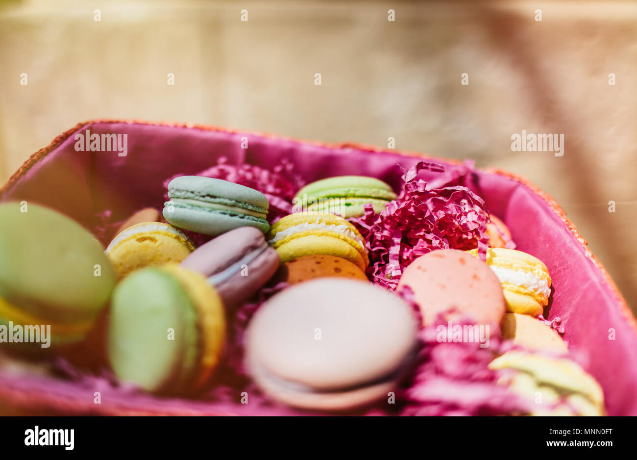 Amaretti colorati e fiori su un tavolo di legno. Dolce macarons in confezione regalo. Lay piatto Foto Stock