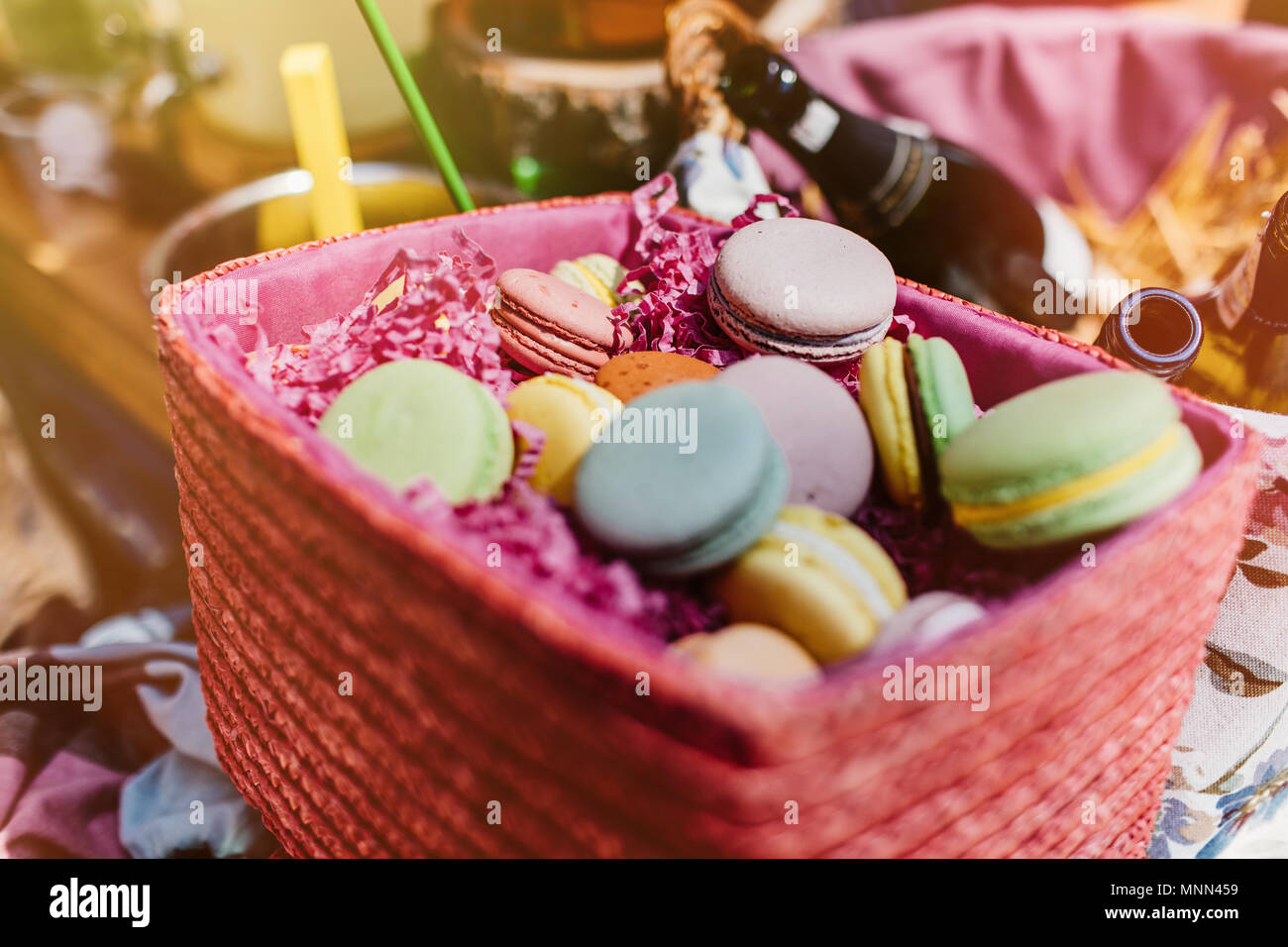 Amaretti colorati e fiori su un tavolo di legno. Dolce macarons in confezione regalo. Lay piatto Foto Stock
