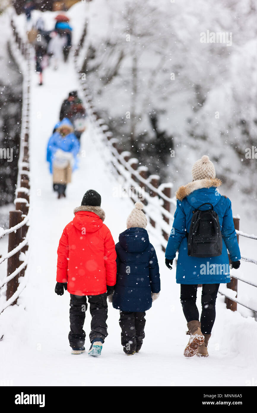 La famiglia di madre e bambini attraversando il ponte sul fiume Shogawa nello storico villaggio giapponese Shirakawa-go in inverno Foto Stock