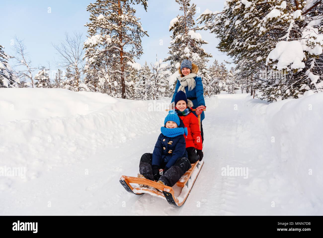 Bella famiglia della madre e bambini godendo nevoso inverno giorno all'aperto avendo divertimento slittino Foto Stock