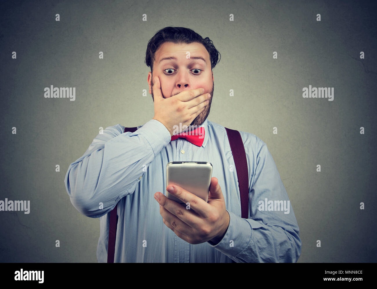 Giovane uomo guardando al suo smartphone con sentimento profondo sconcerto e paura. Foto Stock