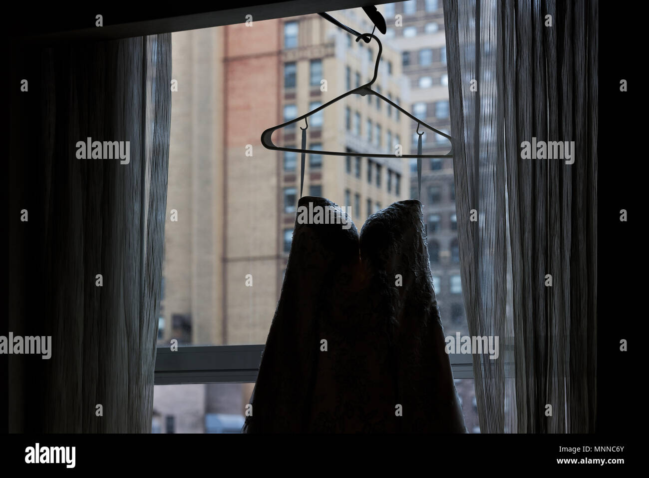 Primo piano di abiti da sposa appeso sulla stampella di finestra, con  persiane, davanzale Urbana di New York City NY NYC hotel highrise  appartamento condominio Foto stock - Alamy
